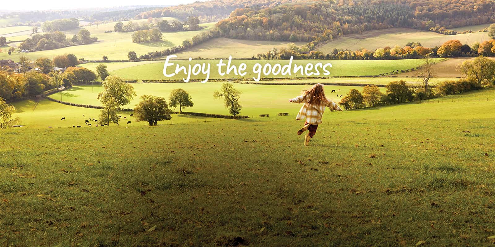 Girl running free across a field with a view of rolling countryside