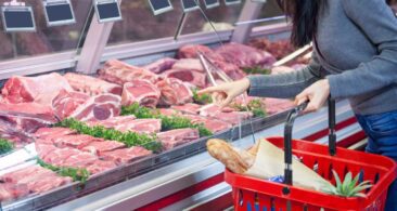 A shopper looking at display of meat at the butcher's counter in a supermarket