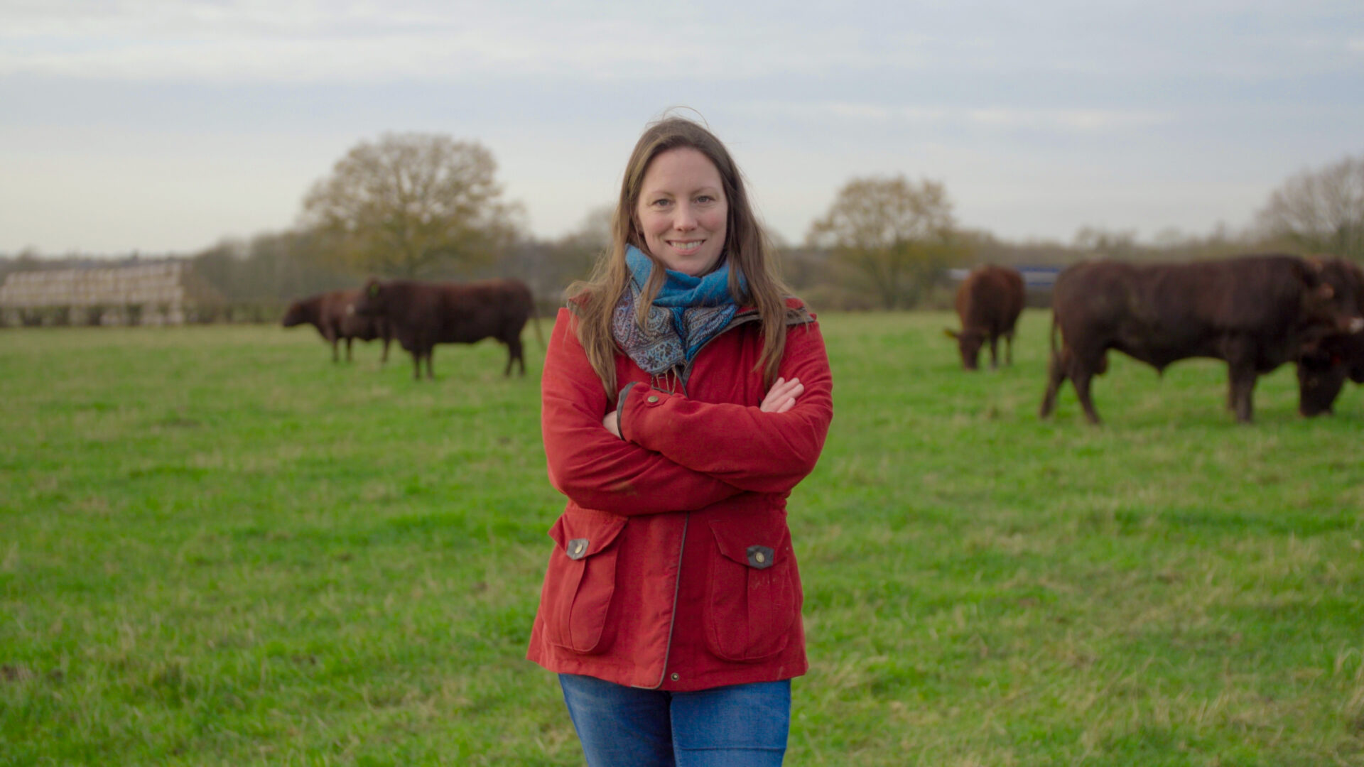 UK livestock farmer Anna Blumfield stood in a field with cows grazing behind her